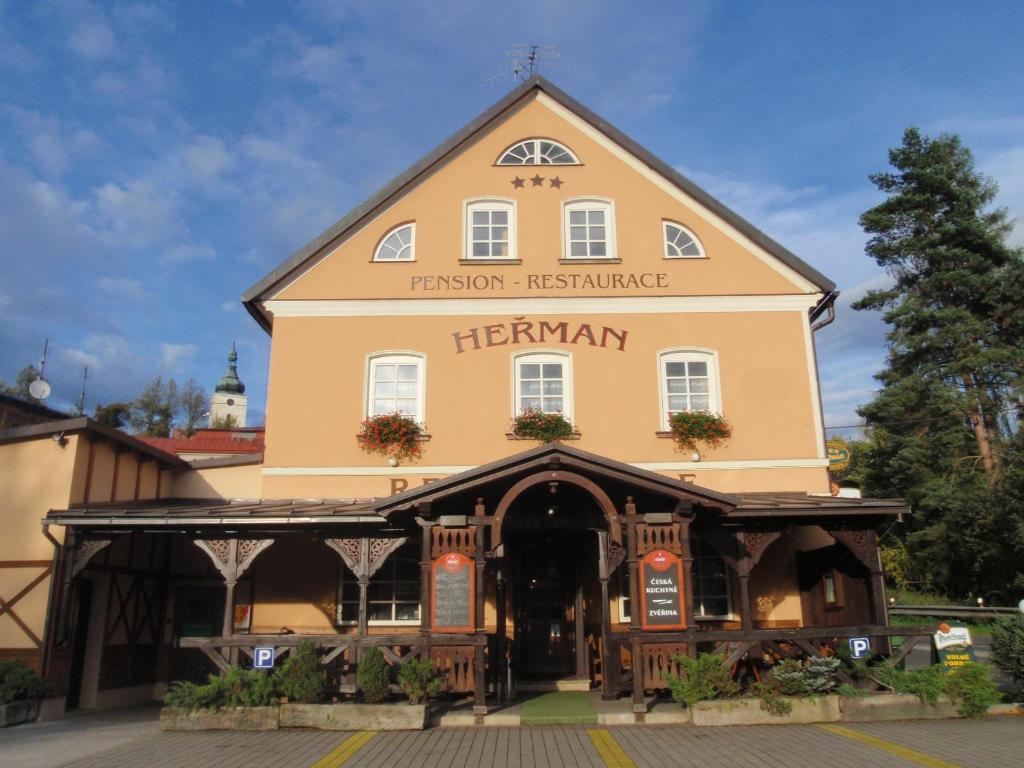 a large yellow building with a sign on it at Pension Herman in Rudník