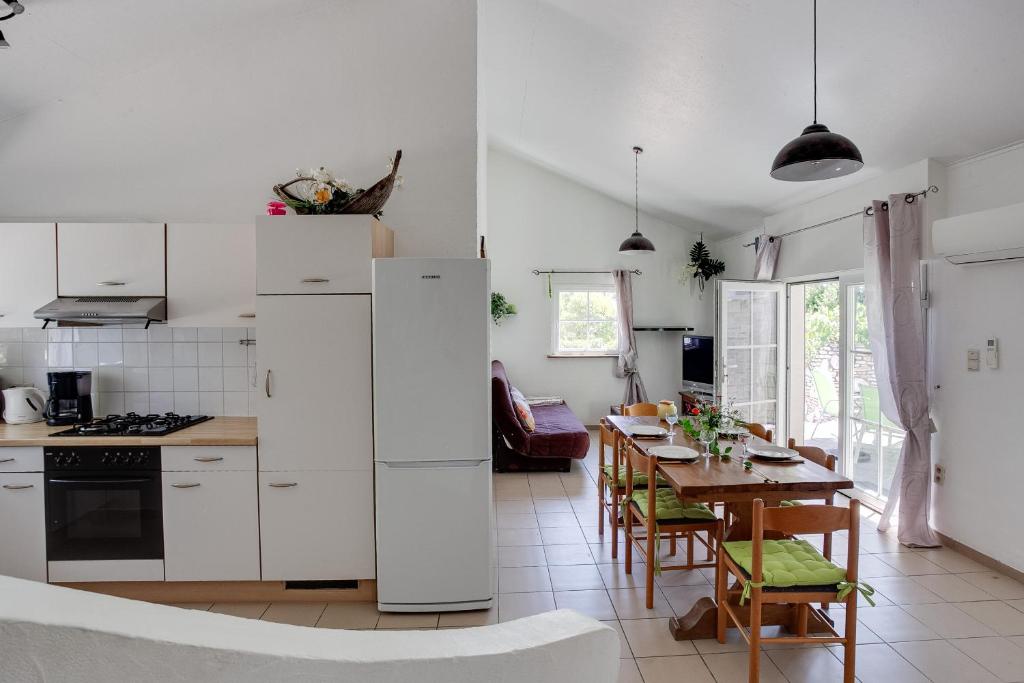 a kitchen with white appliances and a table with chairs at Apartments La Vieille Source in Saint-Martin-dʼArdèche