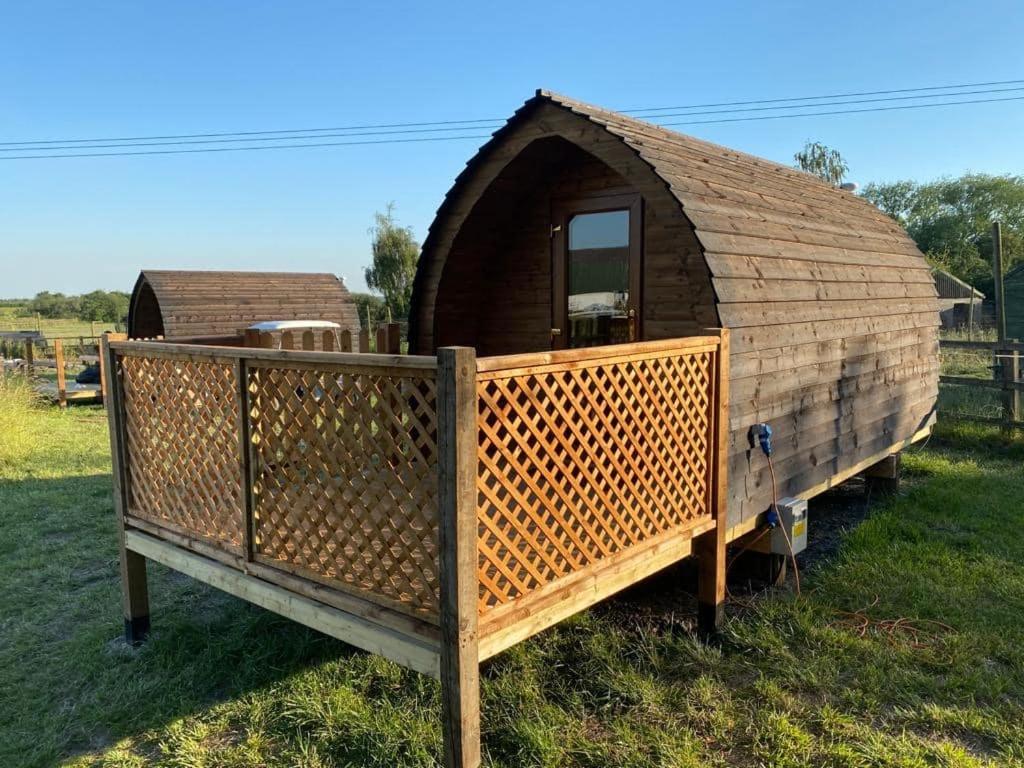 a large wooden dog house sitting in the grass at Glamping pod, seven acre farm campsite in Lincoln