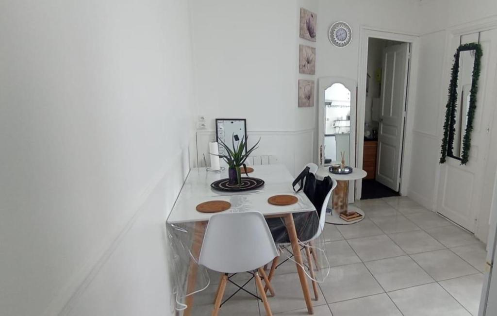 a white kitchen with a table and chairs at katyra house in Aubervilliers