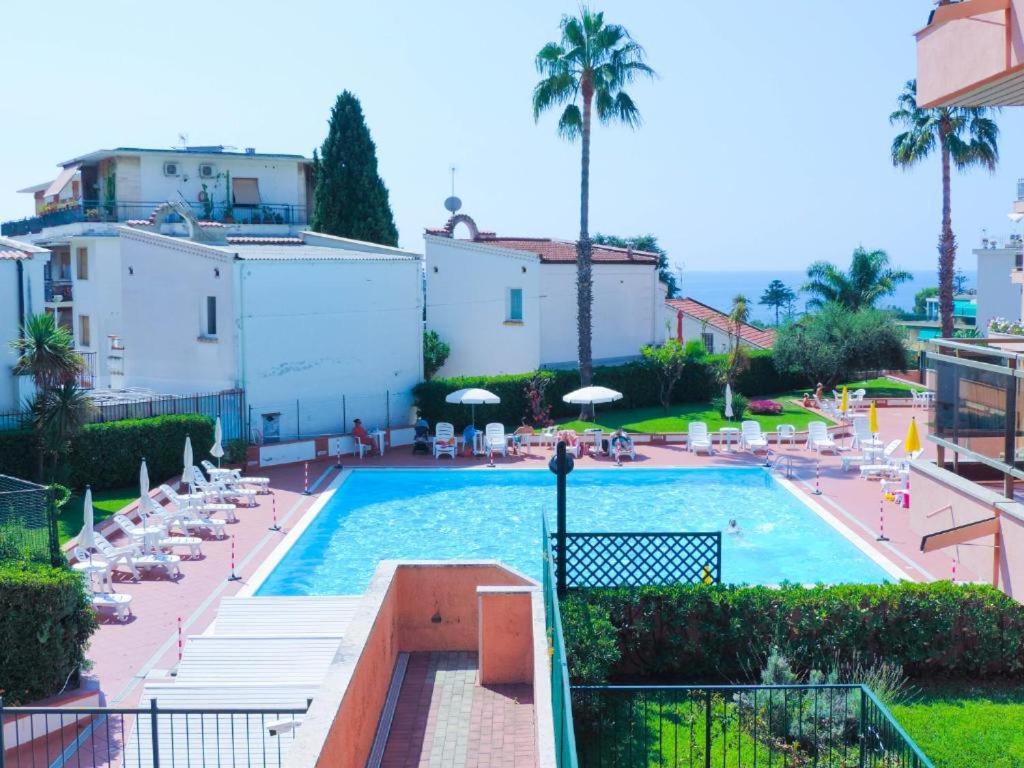 a large swimming pool with chairs and palm trees at baiasole in Sanremo