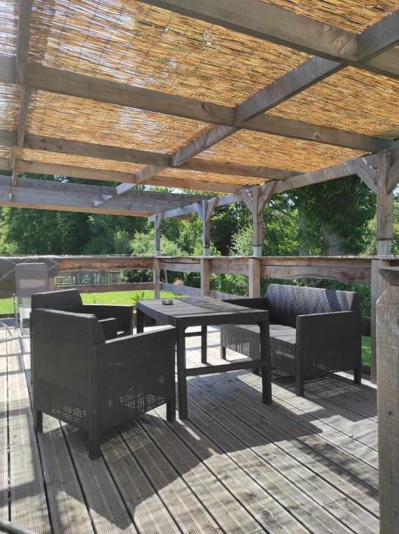 une table de pique-nique et des chaises sous une pergola en bois dans l'établissement le hangar 87, à Bussière-Portevine