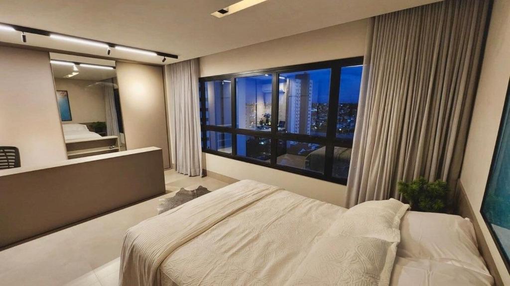 1 dormitorio con cama y ventana grande en Estúdio Completo e de Luxo ao lado Shopping CG., en Campo Grande