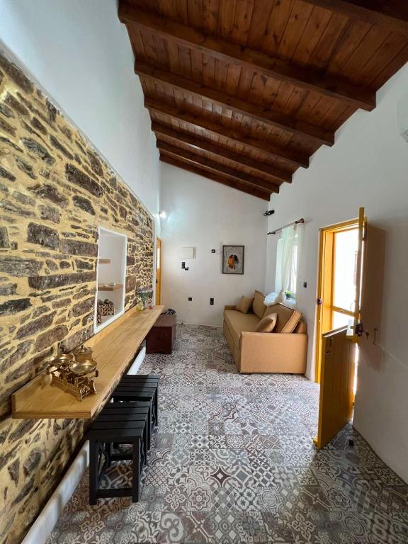 a living room with a couch and a stone wall at Κυθνος Δρυοπίδα, Στούντιο Χατζής in Dhriopís