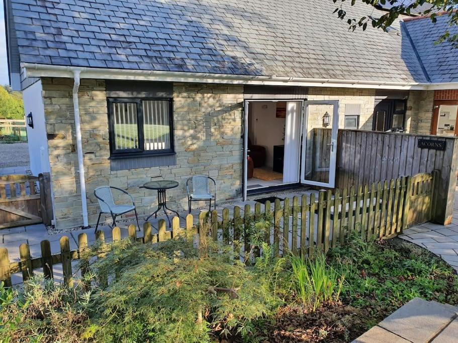 ein kleines Haus mit einem Zaun, einem Tisch und Stühlen in der Unterkunft Modern, self-contained annexe in the countryside in Callington