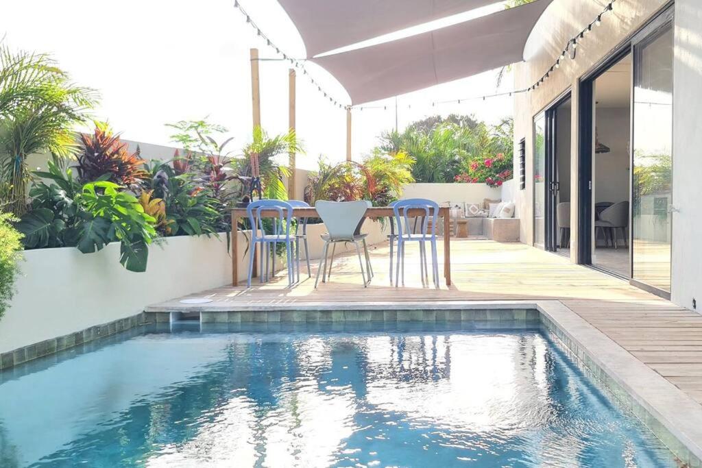 a swimming pool with chairs and a table next to a house at Boutique appartment 4P with PRIVATE POOL, close by Jan Thiel & Mambo beach in Willemstad