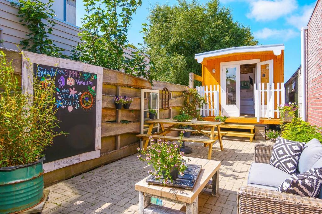 a patio with a chalkboard and a tiny house at In Ons Tuintje - aan zee - Callantsoog in Callantsoog