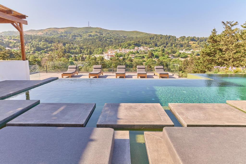 een zwembad met ligstoelen en een berg bij Kanevos Iconic Villa with private heated lap pool! in Kánevos