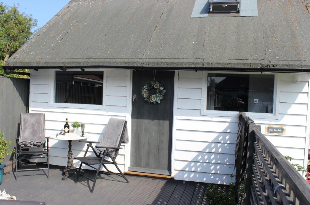 a white house with a table and chairs on a deck at The Bubble Hideaway - A Little Oasis near the Sea in Whitstable