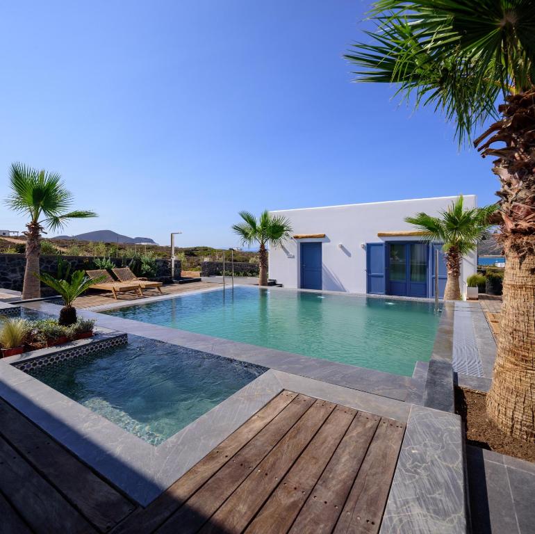 a swimming pool with a wooden deck and palm trees at White Dream Suites Antiparos in Antiparos
