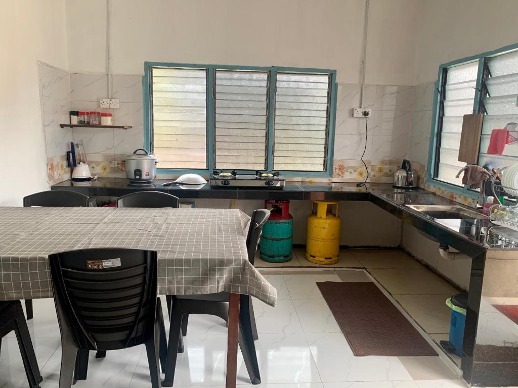 cocina con mesa, sillas y fregadero en Homestay Bajet MokAji, en Kuala Terengganu