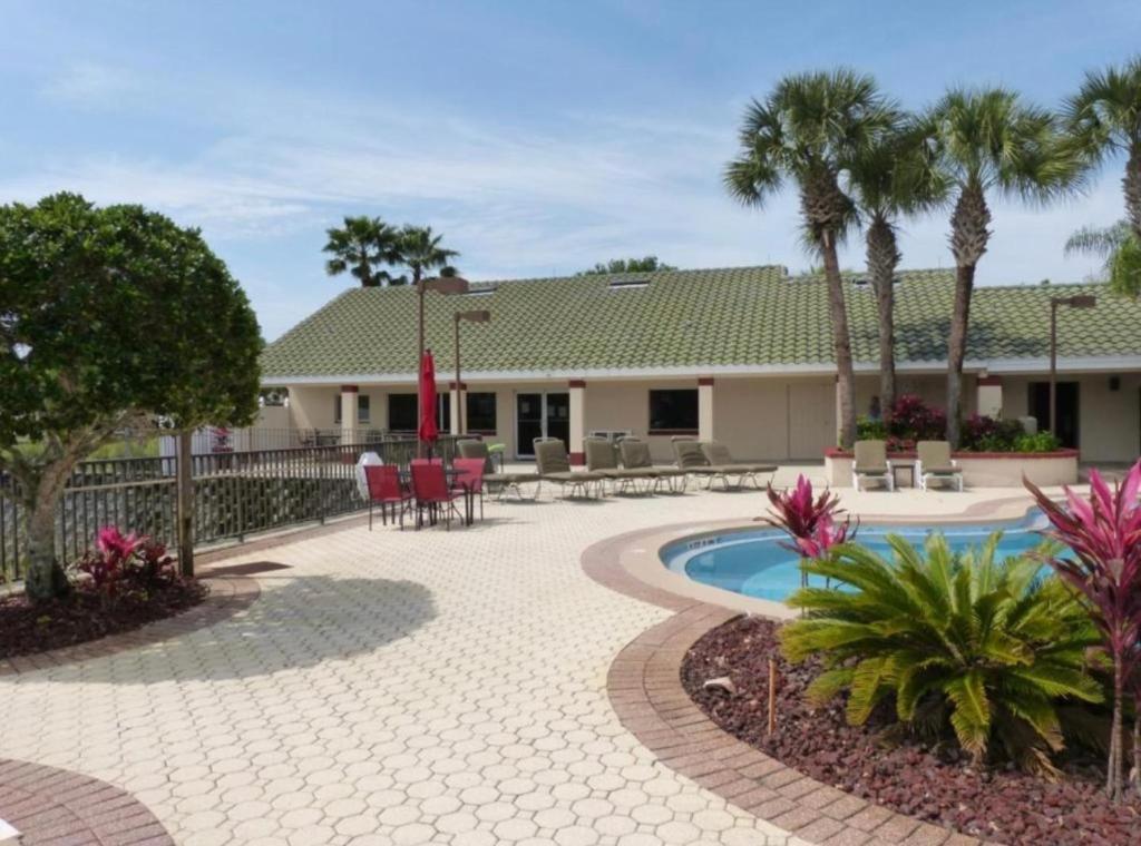a patio with a pool and a house with palm trees at Disney Holiday Home, Orlando in Kissimmee