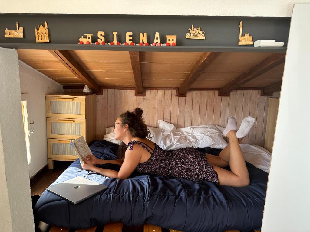 uma mulher deitada numa cama com um portátil em Panoramic lovely time em Siena