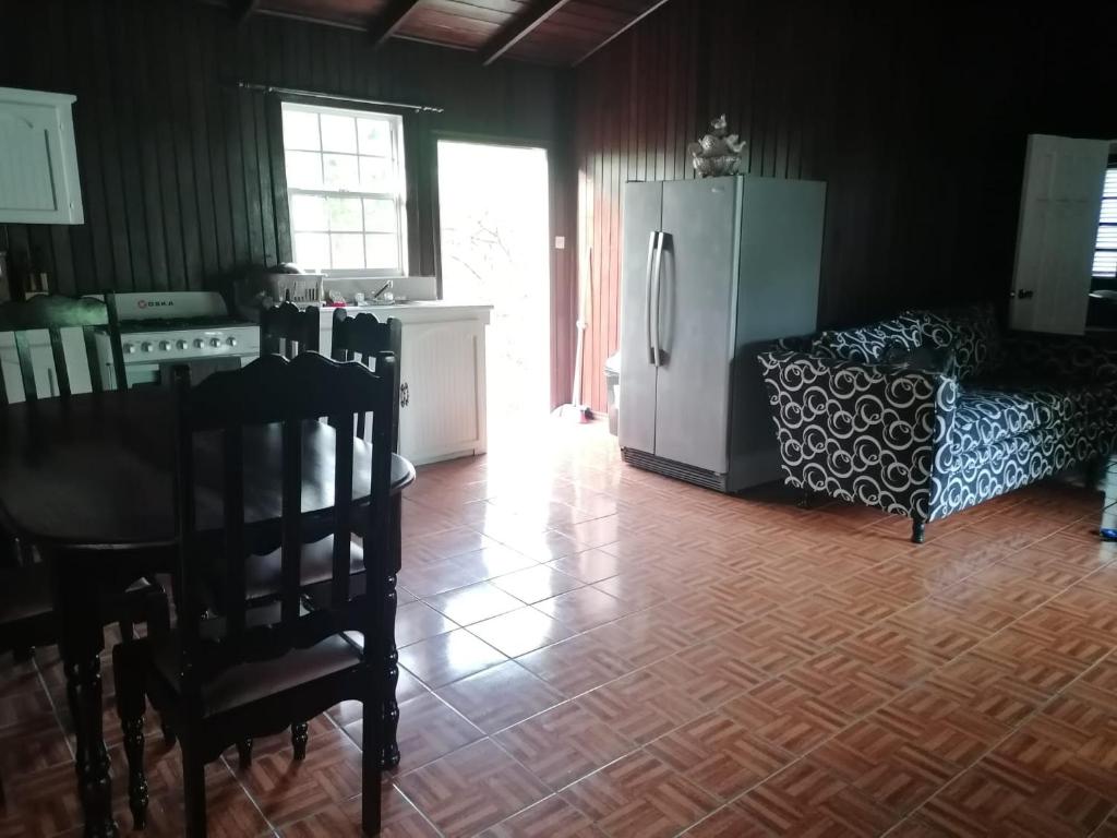 cocina con nevera, mesa y sofá en Belle Breeze Cottage en Gros Islet