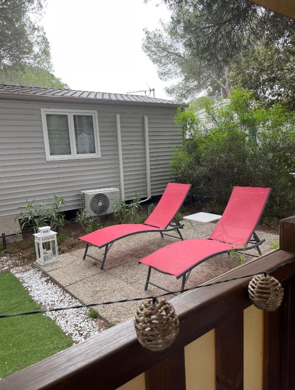 two pink chairs on a deck with a house at Camping Oasis village in Puget-sur-Argens