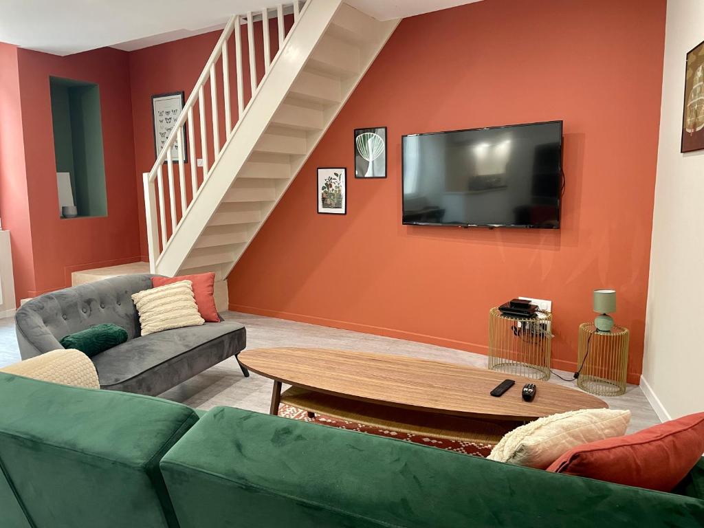 a living room with a couch and a tv at Gîte les Pissenlits centre historique Saint-Astier in Saint-Astier