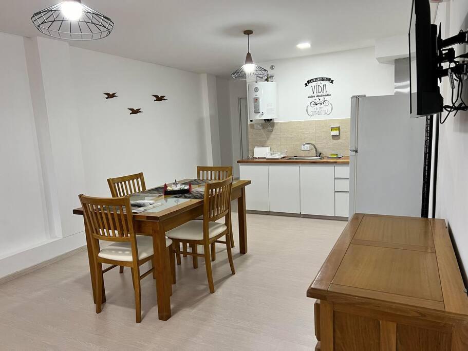 cocina con mesa, sillas y nevera en apart trelew 1 en Trelew