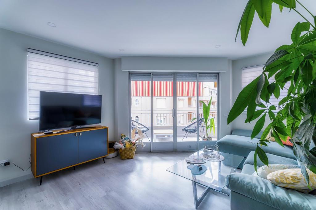 uma sala de estar com um sofá azul e uma televisão em Palangre Beach Apartment em Torrevieja