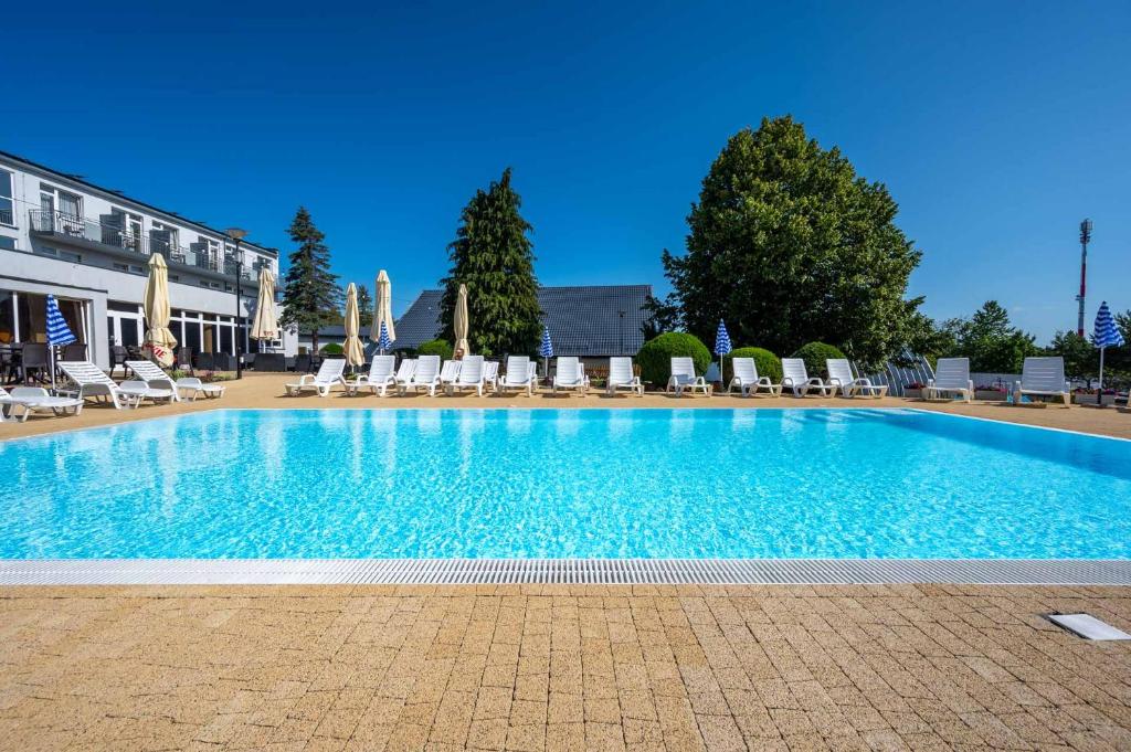 a large swimming pool with lounge chairs and a building at Albatros Spa & Ski in Jarosławiec