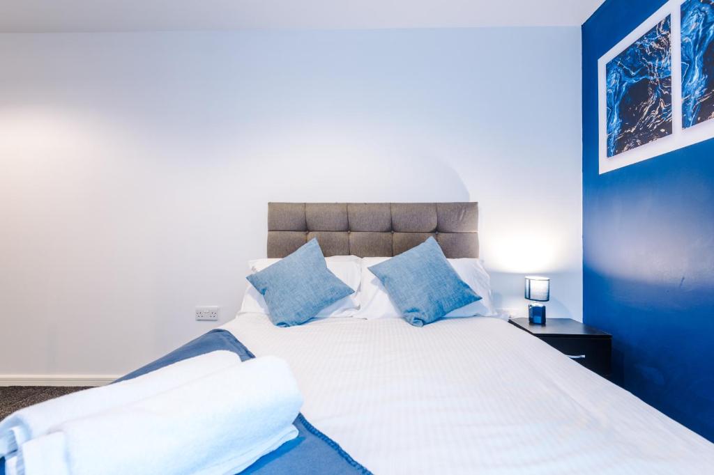 een blauwe slaapkamer met een wit bed met blauwe kussens bij 2 Bed apartment with balcony private parking near Etihad Stadium, COOP Live in Manchester