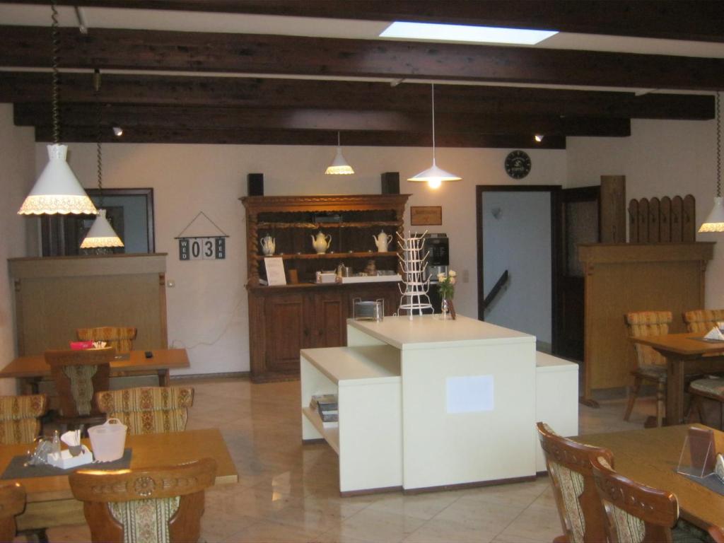 a dining room with tables and chairs and a kitchen at Hotel am Weißdornbusch in Gifhorn