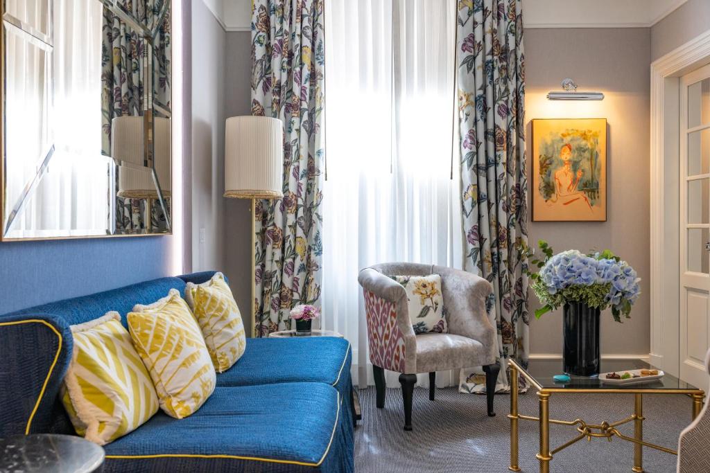 uma sala de estar com um sofá azul e uma cadeira em Maalot Roma - Small Luxury Hotels of the World em Roma