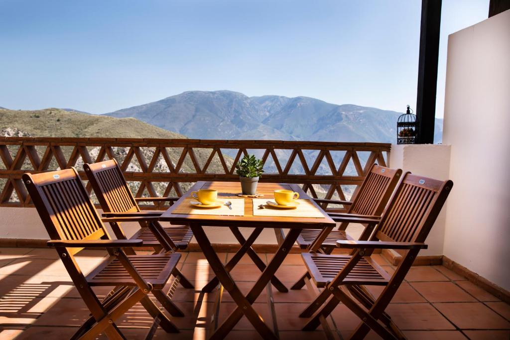 een houten tafel en stoelen op een balkon met uitzicht op de bergen bij tuGuest Carataunas Apartment Alpujarra VI in Carataunas