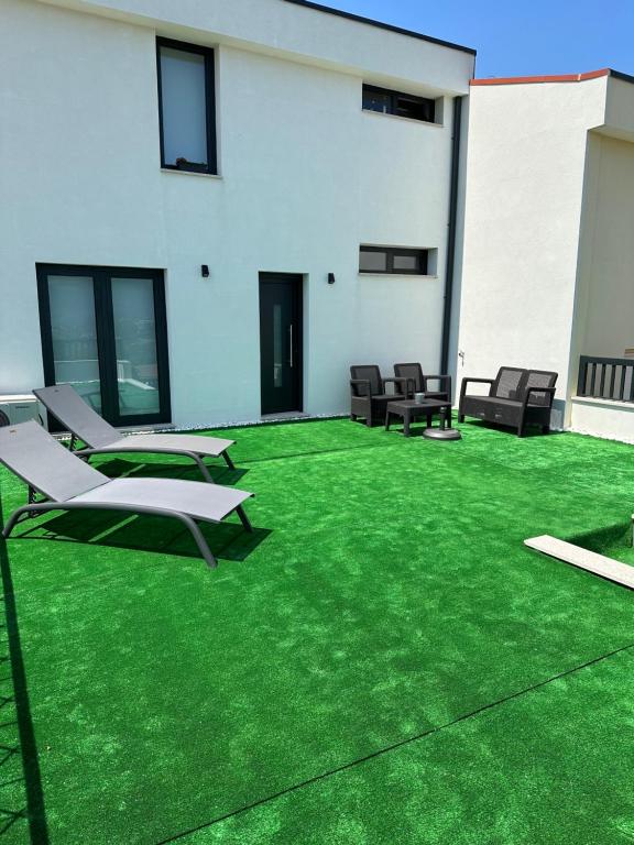 un patio con césped y sillas verdes y un edificio en S&C HOSTING, en Celorico de Basto