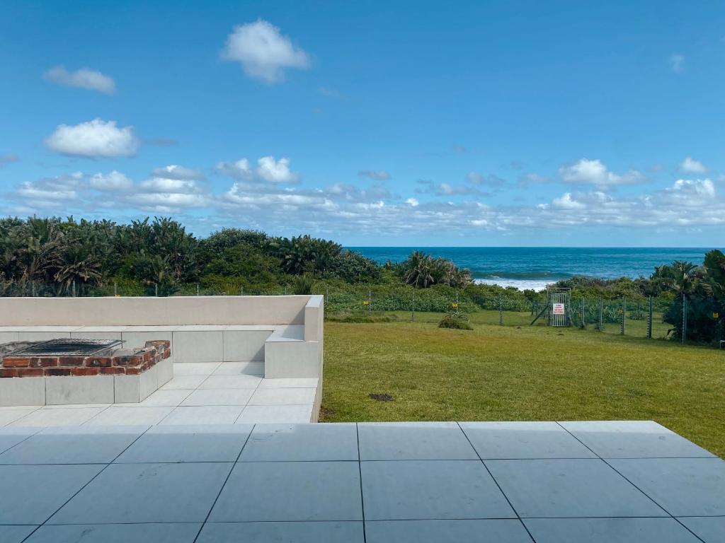 un patio con chimenea y vistas al océano en Tamassa Holiday Home on the Beach, in Port Edward, en Port Edward