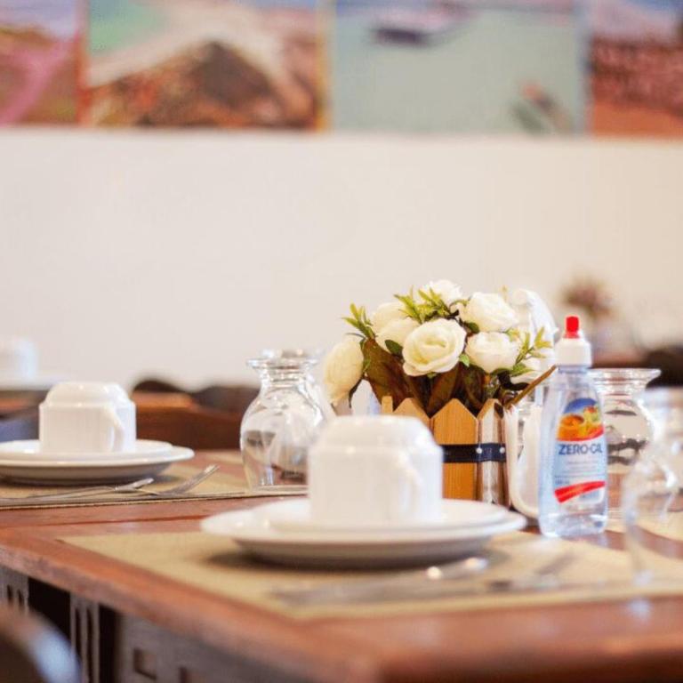 a table with white plates and a vase of flowers at Happy Hotel Brisa do Mar in Ipojuca