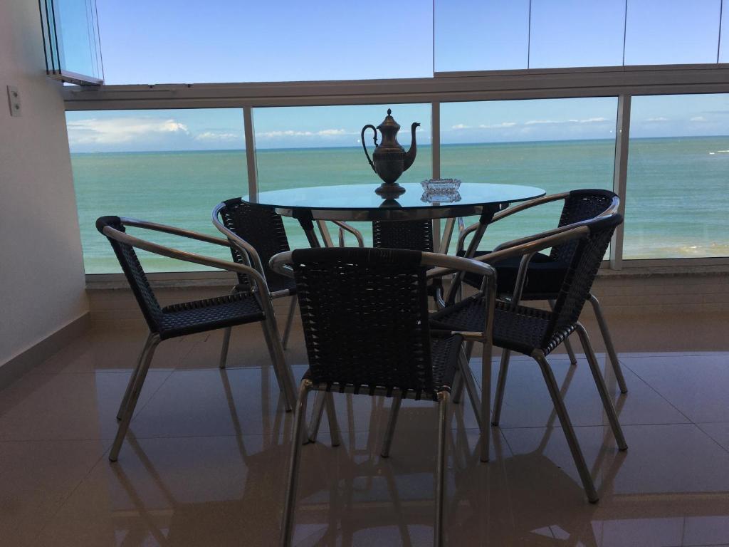 ein Tisch und Stühle mit Blick auf das Meer in der Unterkunft Apto Luxo frente praia do Morro in Guarapari