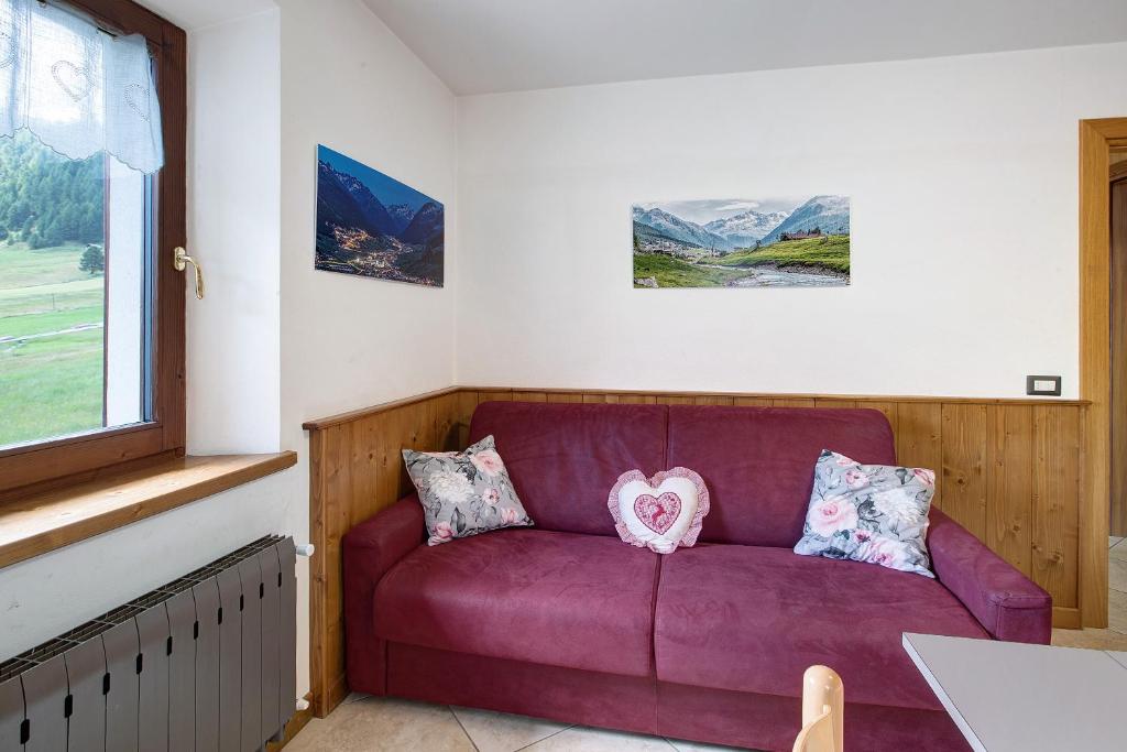 un sofá púrpura en una habitación con ventana en Appartamento Bormetti Paolo Sara, en Livigno