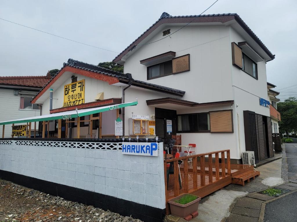 een wit gebouw met een bord ervoor bij 하루카오후나에 민숙 in Tsushima