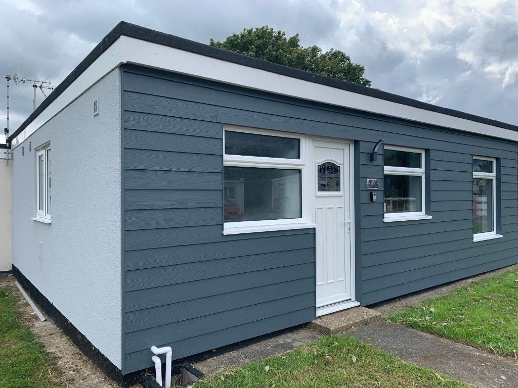 a blue and white shed with a door and two windows at Salty Dogs Chalet in Lowestoft