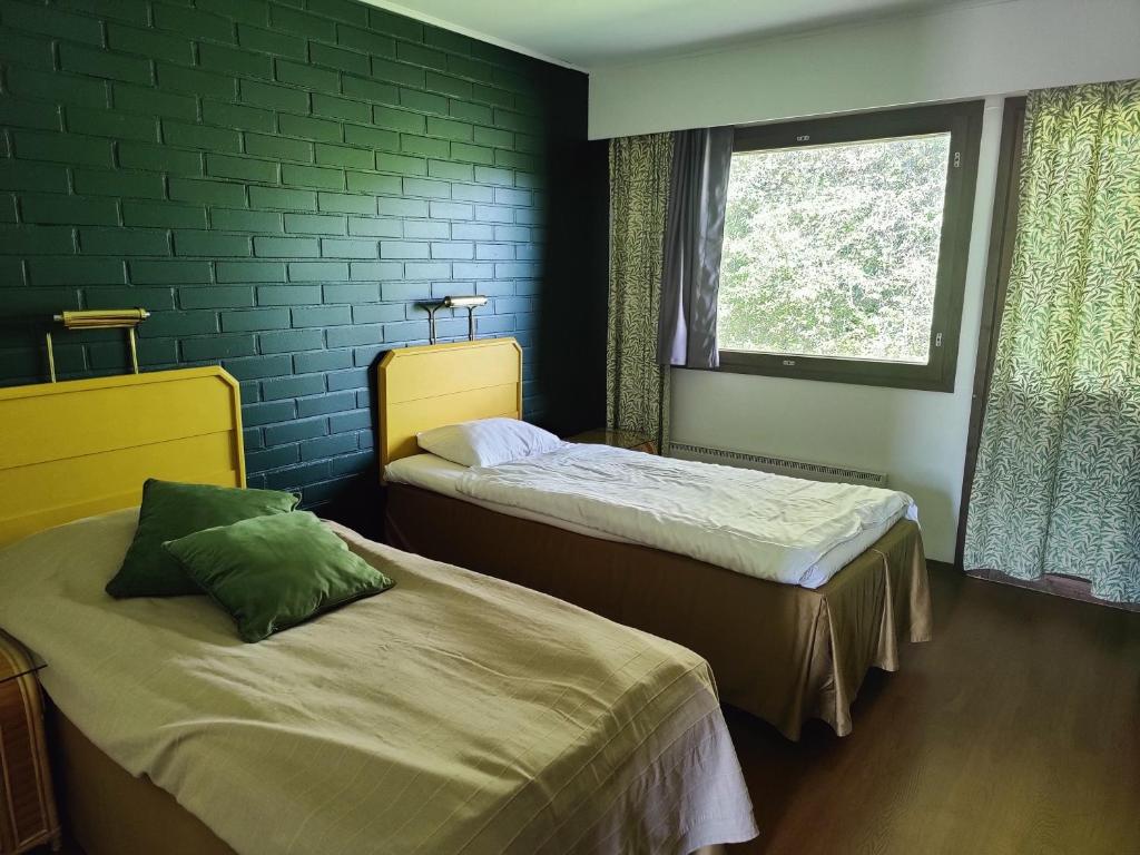 Cette chambre comprend 2 lits et une fenêtre. dans l'établissement Jokirannan Majoitus, à Kokemäki