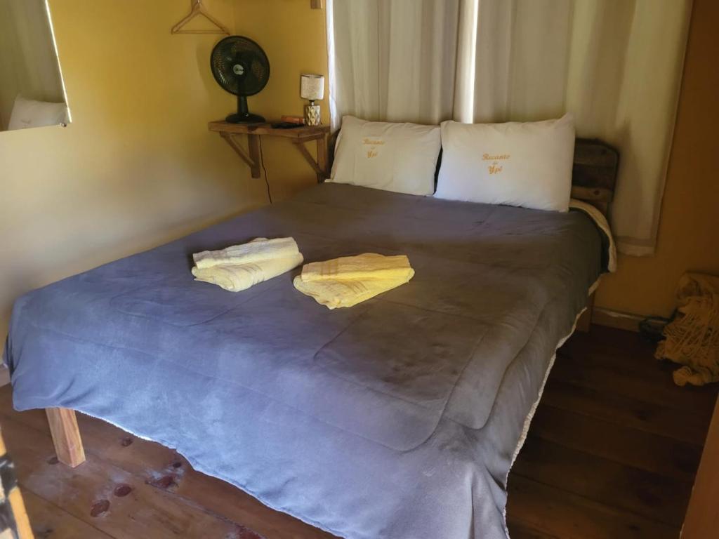 a bed in a room with two towels on it at Pousada Recanto do Ypê in Aiuruoca