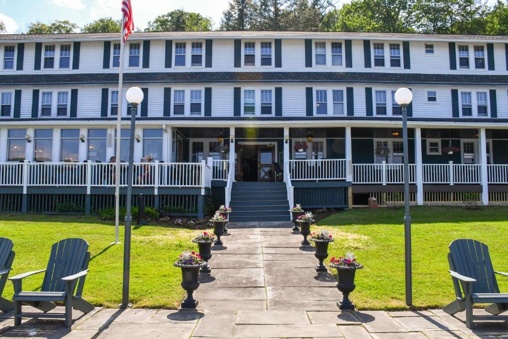 a large blue house with chairs in front of it at Chestnut Inn at Oquaga Lake in Deposit