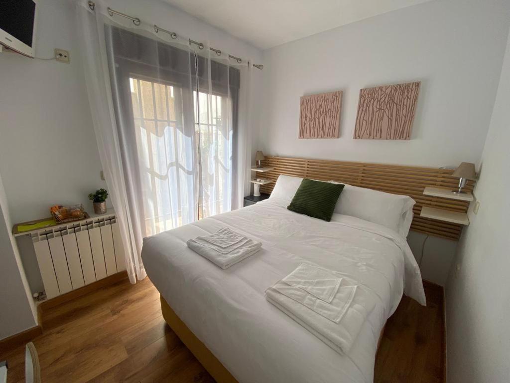 1 dormitorio con 1 cama blanca grande y 2 toallas en Habitación intima con patio privado, 