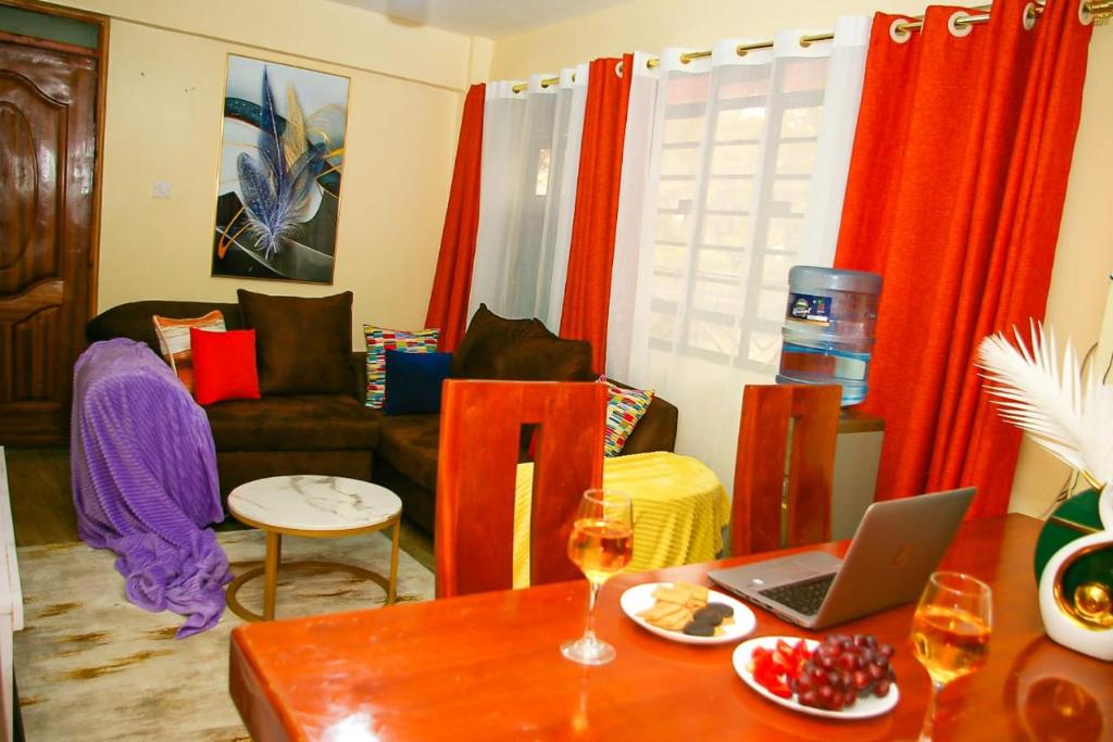 ein Wohnzimmer mit einem Tisch und einem Laptop darauf in der Unterkunft Jaymorgan' Cabins. in Nyeri