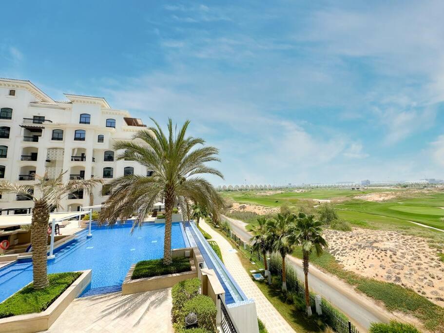 een uitzicht op een hotel met een zwembad en palmbomen bij Luxury Golf View For Family 203A3 in Abu Dhabi