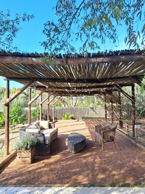 une pergola en bois avec deux canapés et un banc dans l'établissement Olive grove cottage, à Koringberg