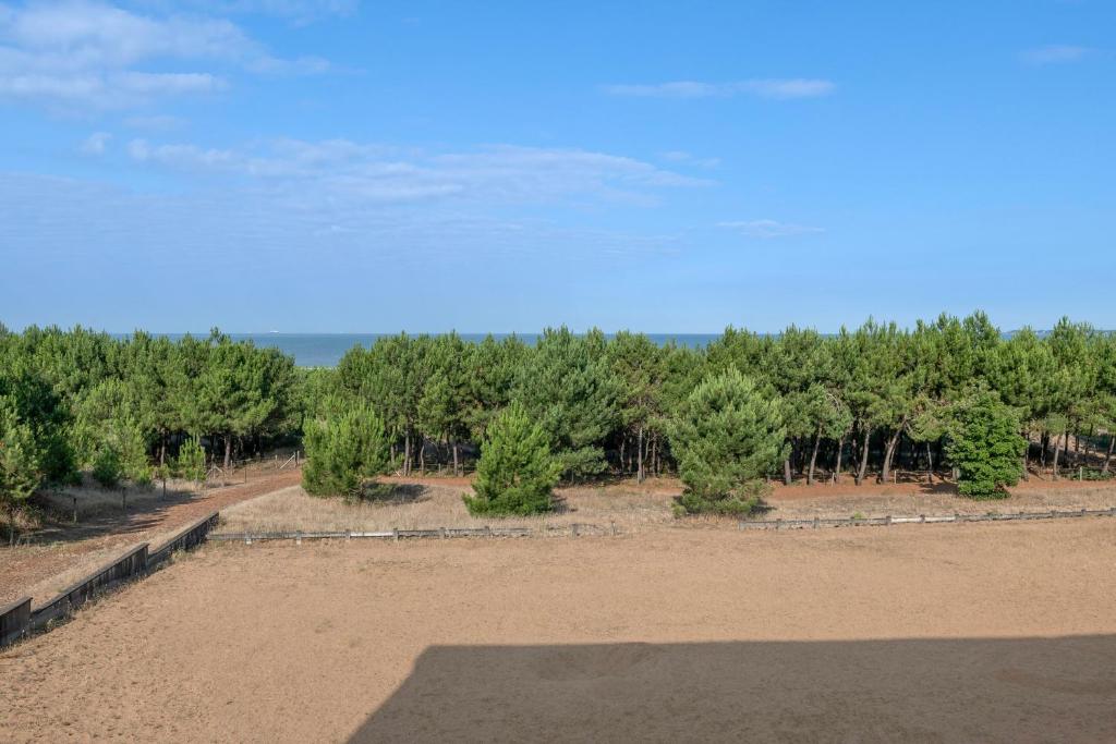 une vue sur un champ de terre avec des arbres en arrière-plan dans l'établissement Face mer appartement pour 4 à Saint Brévin, à Saint-Brévin-les-Pins