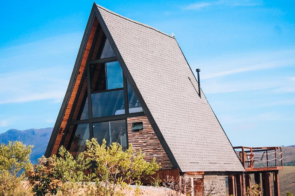 a house with a shingled roof and large glass windows at Canda Cabana com SPA e vista para Cachoeiras in Baependi