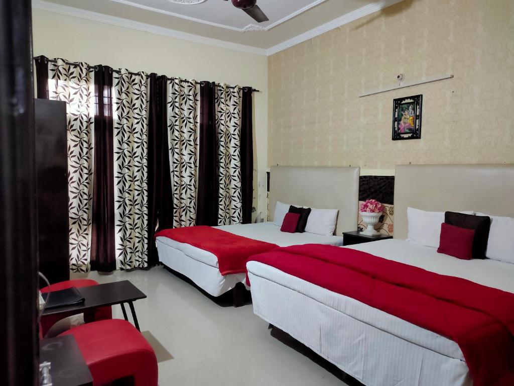 Habitación de hotel con 2 camas con sábanas rojas en New Chandigarh Holiday Home, en Chandīgarh