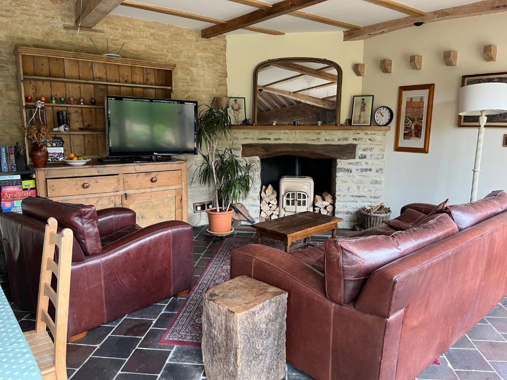 a living room with leather couches and a fireplace at The Arches - Private woods, comfy beds, fast Wi-Fi, SkyNetflix in Wellingborough