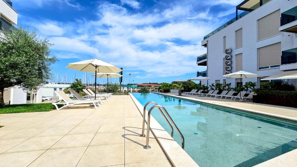 una piscina con sedie e un ombrellone accanto a un edificio di Green Oasis B7 a Novigrad Istria