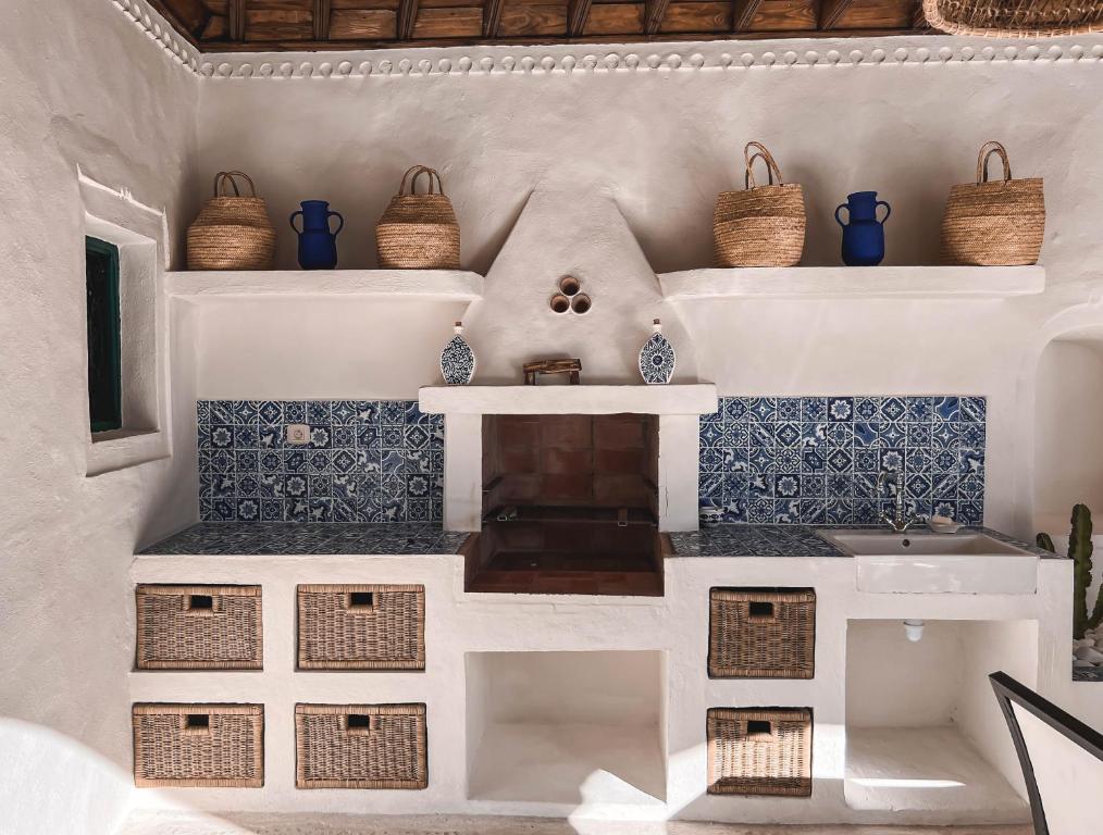 a kitchen with blue and white tiles and baskets at Dar Naël in Houmt Souk