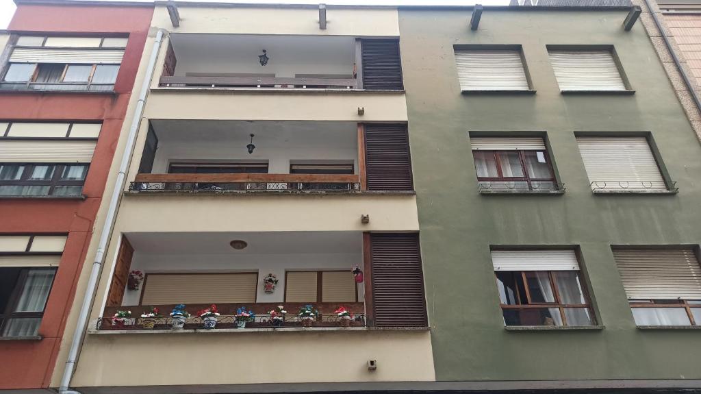 an apartment building with a balcony with flowers on it at Apartamento Casa Belén Arriondas in Arriondas