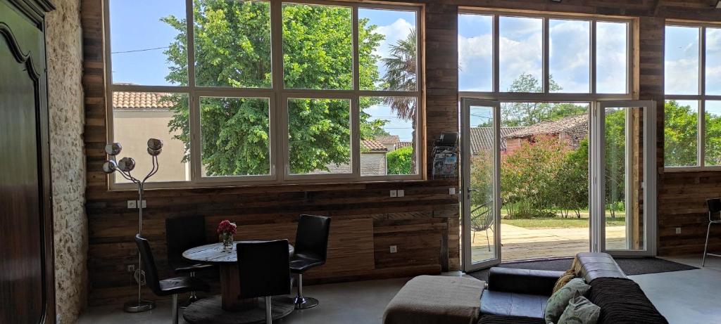 salon z oknami, kanapą i stołem w obiekcie Magnifique Grange Entièrement Rénovée w mieście Marcillac