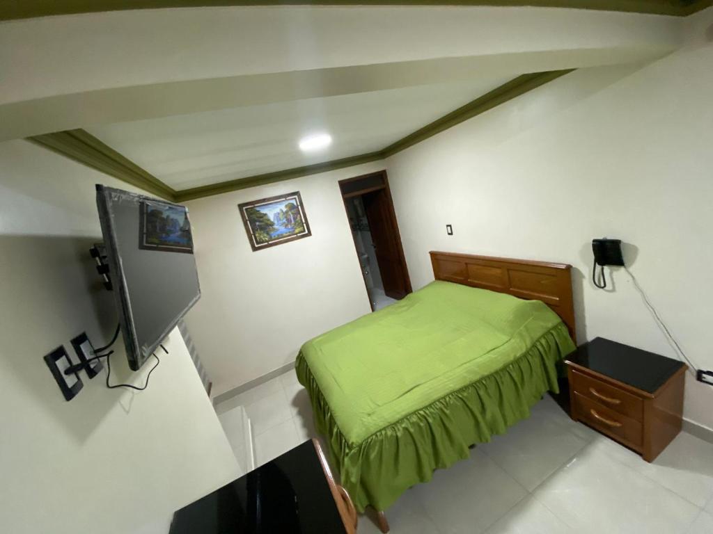 a small bedroom with a green bed and a tv at Hostal Los Pozos in Potosí